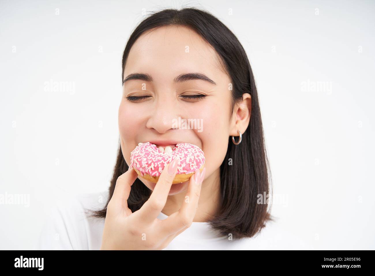 Food and eating out. Young korean woman looks, takes bite of delicious