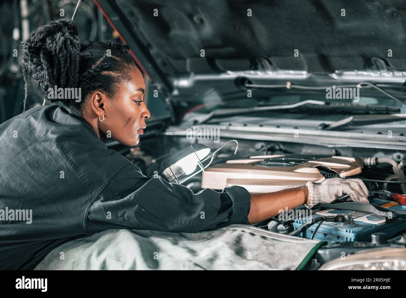 Experienced auto mechanics inspect car battery terminals and voltage to