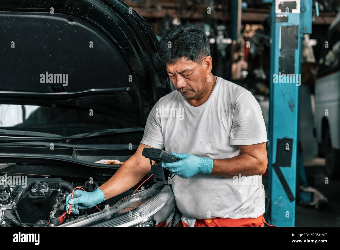 Experienced auto mechanics inspect car battery terminals and voltage to