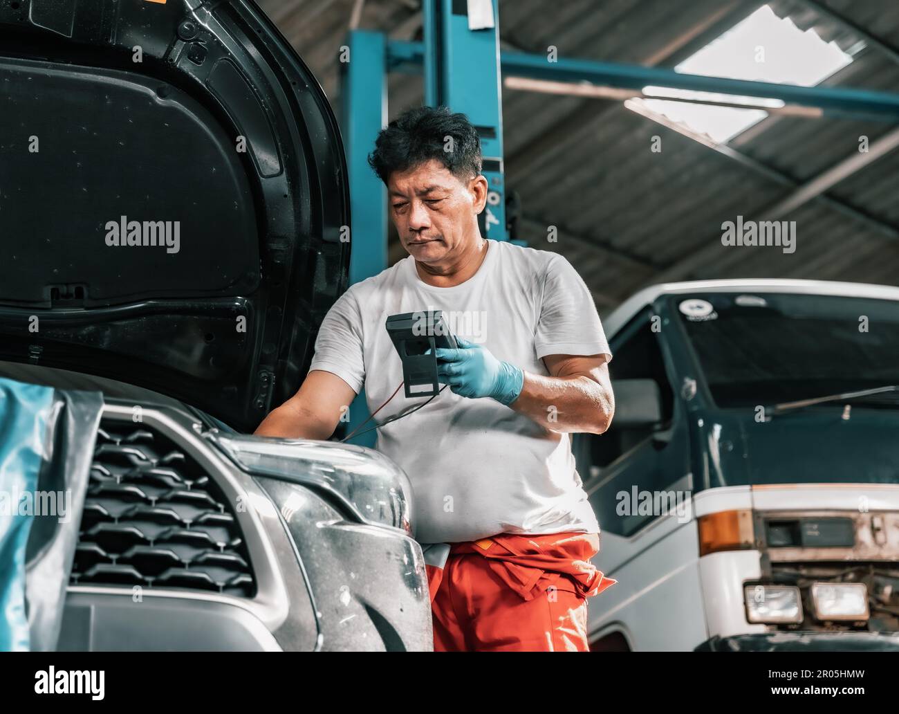 Experienced auto mechanics inspect car battery terminals and voltage to