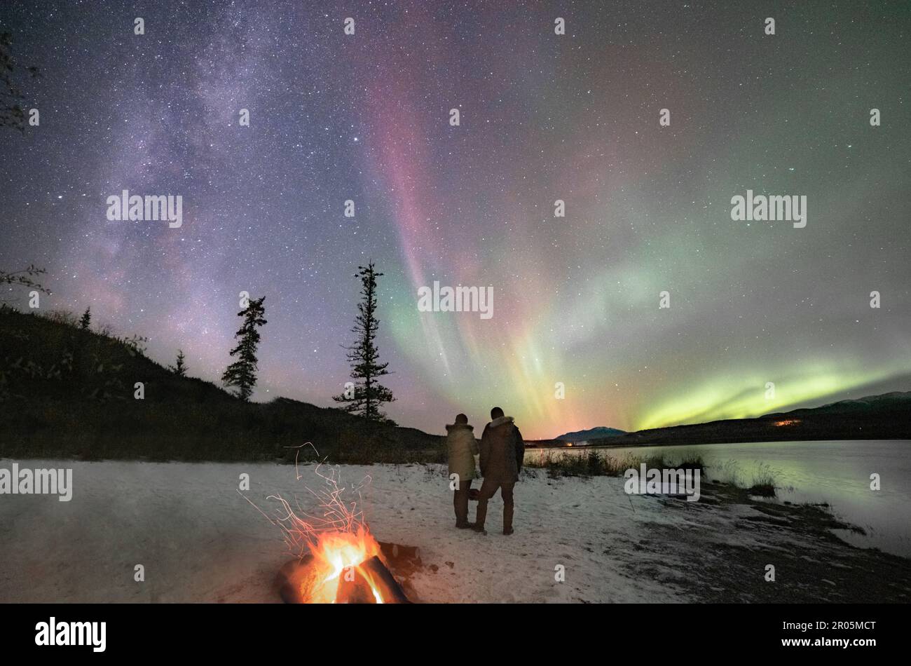 Two people standing under the Aurora Borealis in winter season with ...