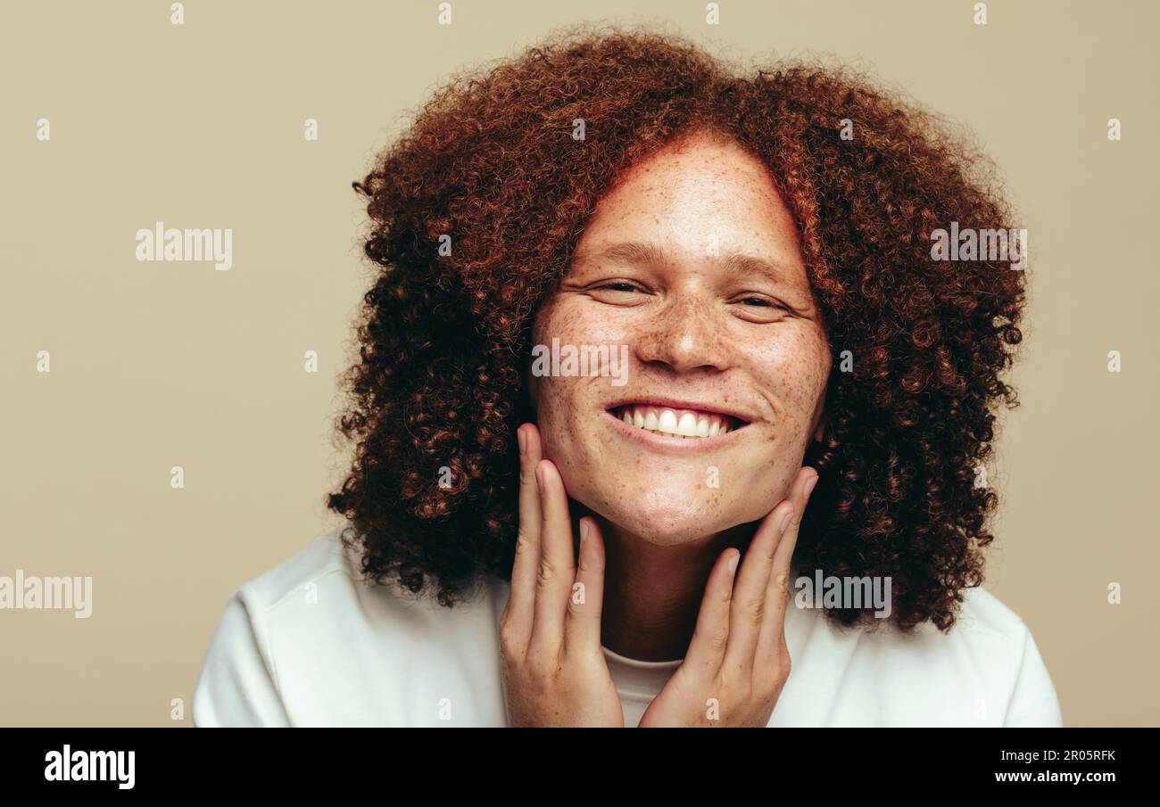 Happy young man smiling with confidence as he embraces and takes care of his natural beauty. Man with a freckled face admiring his flawless and unique Stock Photo