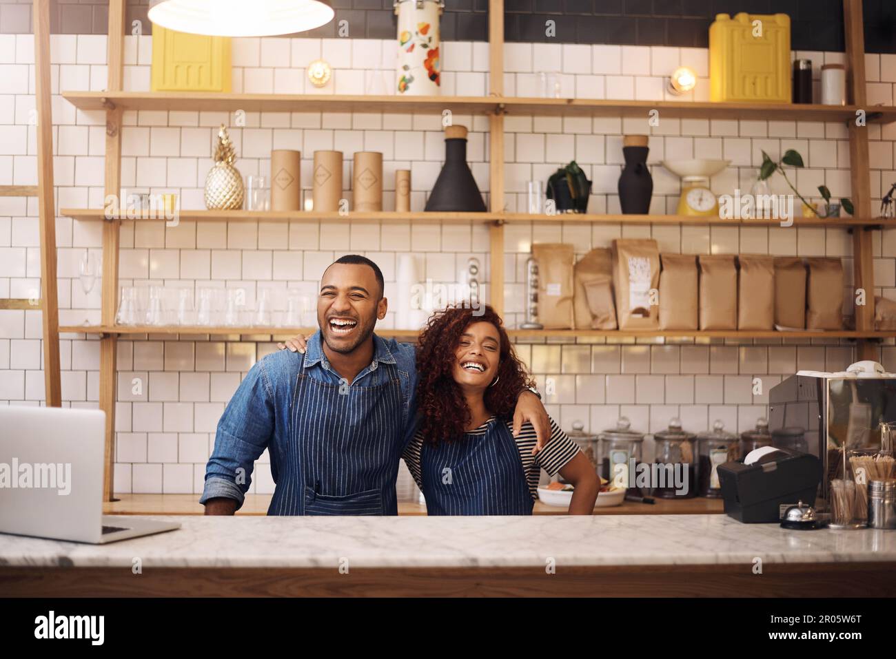 Look at what we created. two young business owners standing in their cafe with their arms around each other. Stock Photo
