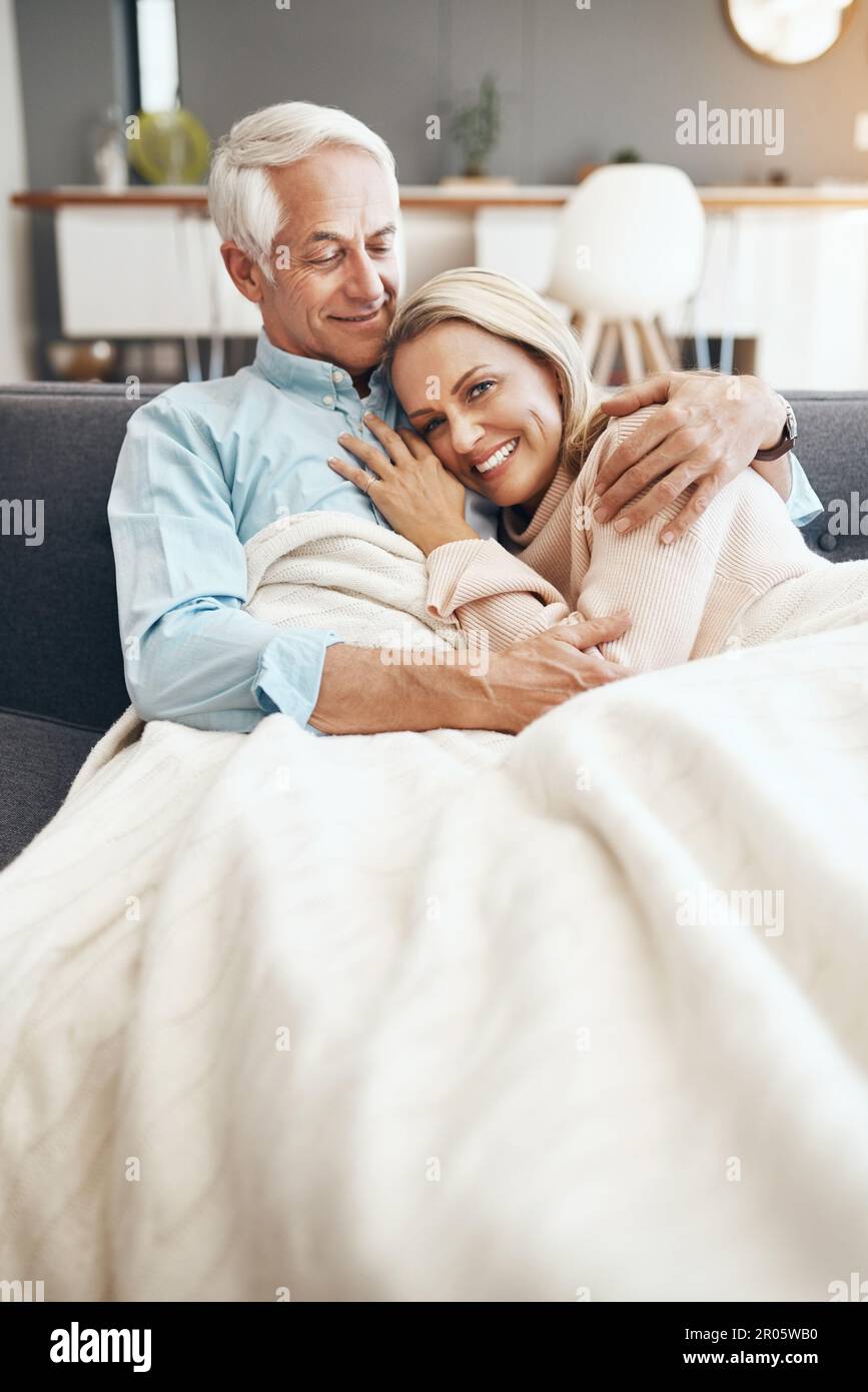 Always make time to relax with your love one. an affectionate mature couple  relaxing on the sofa at home Stock Photo - Alamy