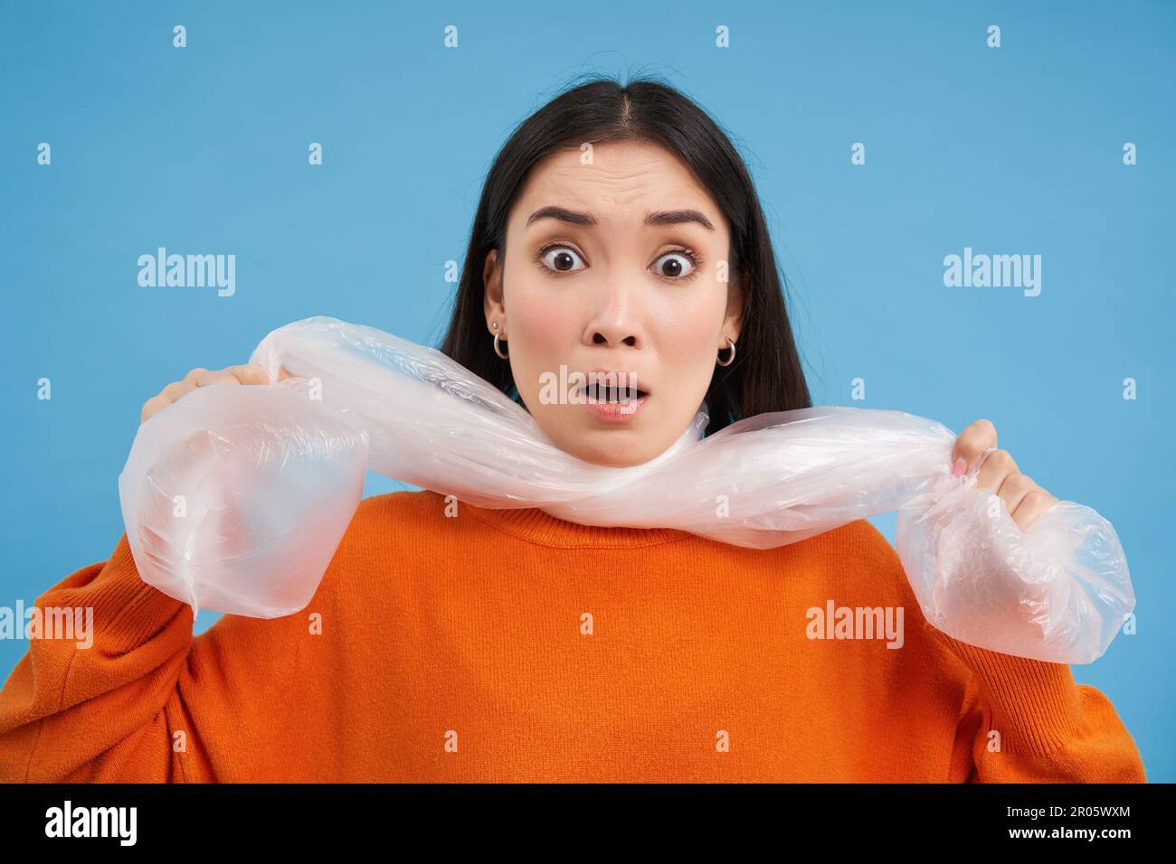 Portrait of young woman being choked by plastic bags, concept of