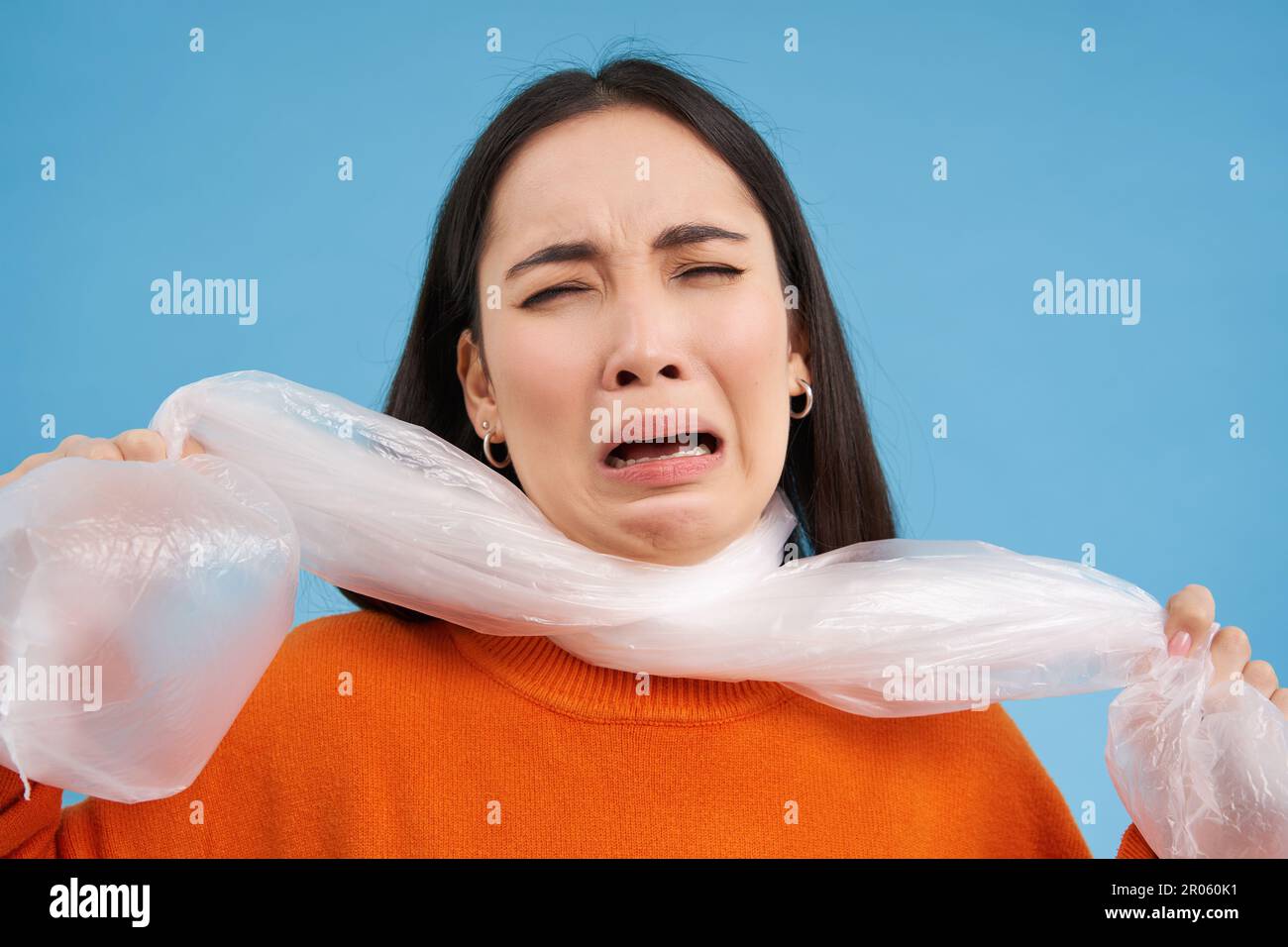 Woman suffocating, being choked by plastic bag, concept of ecology