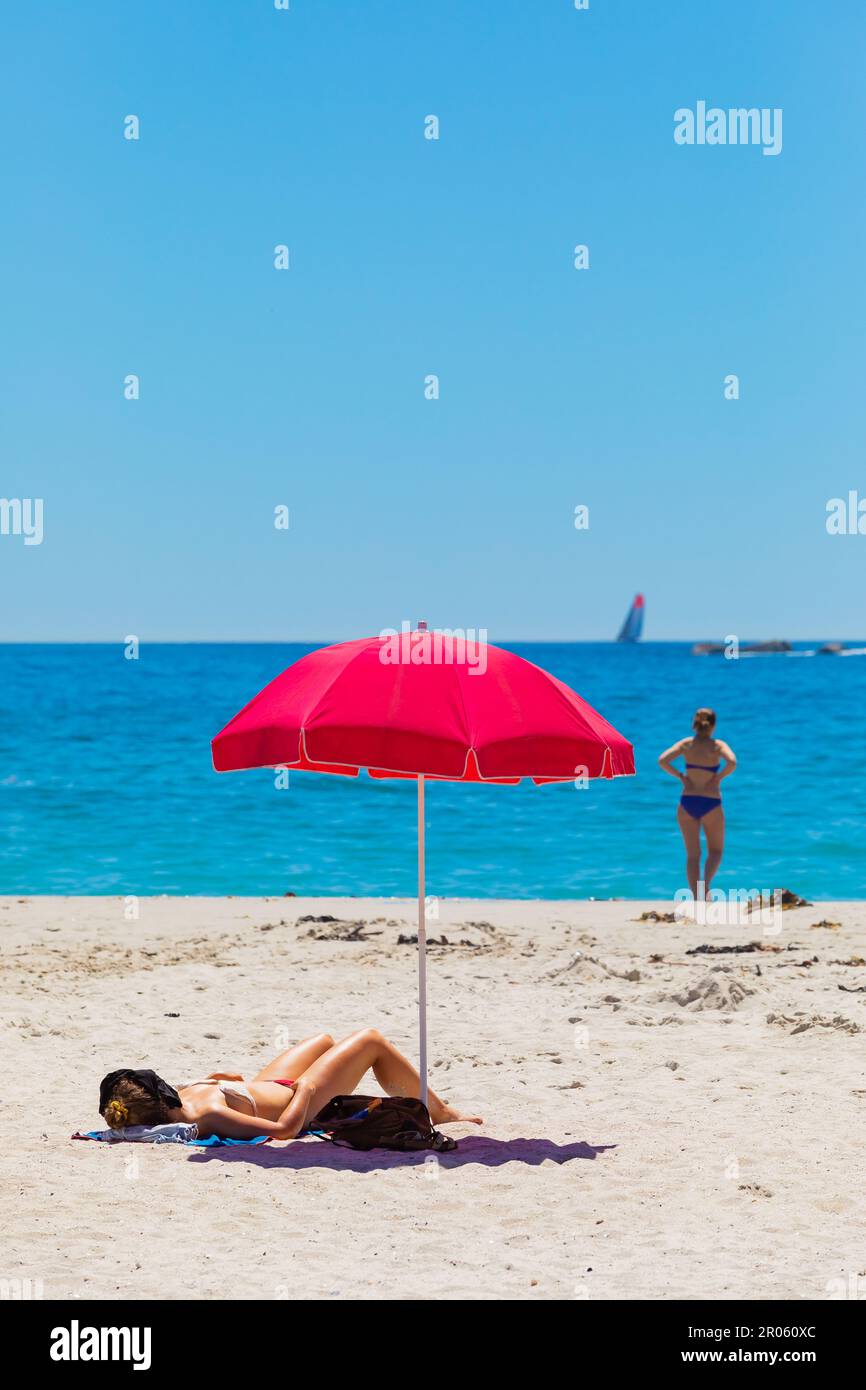 female-vacationers-suntanning-on-sandy-beach-in-camps-bay-cape-town