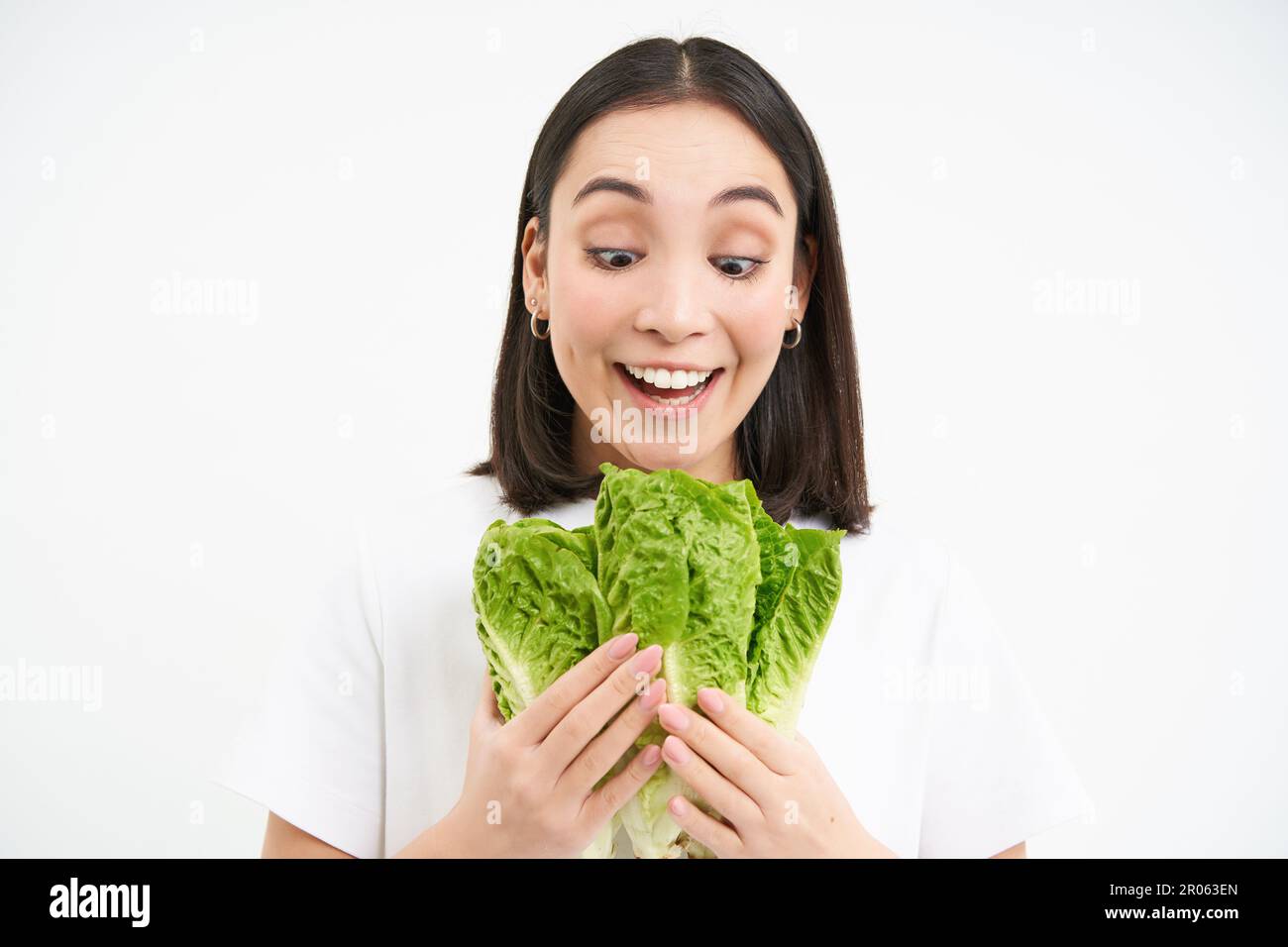 Vegetarian nutrition. Smiling happy young woman looks at her self grown cabbage, eating lettuce