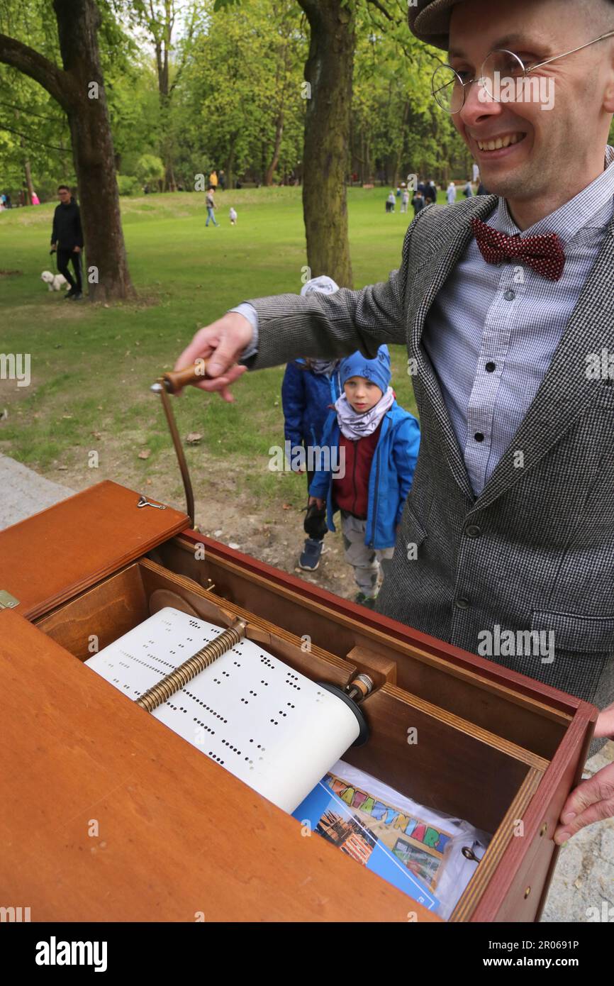 Cracow. Krakow. Poland.Male vintage costumed street entertainer busking in the park playing barrel organ. Inside of the instrument with organ pipes an Stock Photo