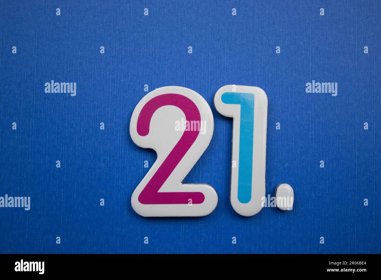 The number 21, placed on a blue background, photographed from above, colored red and light blue. Stock Photo