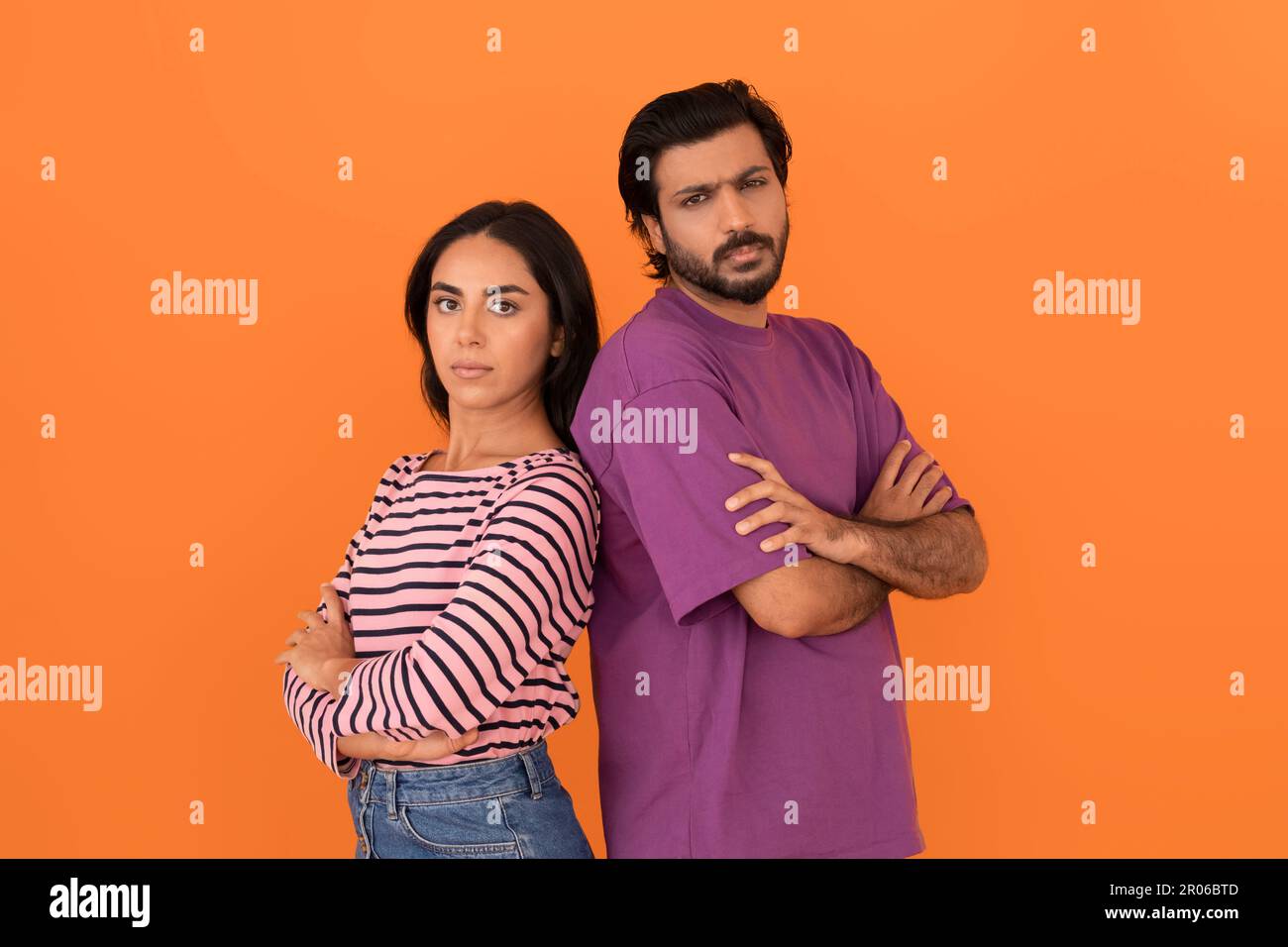 Upset indian couple standing back to back on orange background Stock Photo
