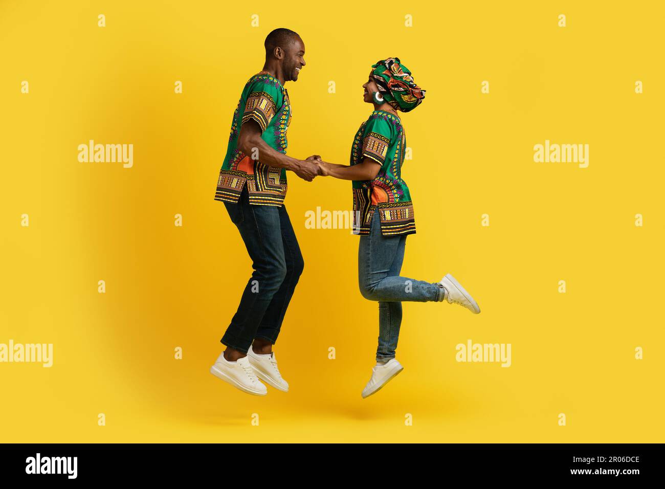 Emotional african couple holding hands and jumping up Stock Photo - Alamy