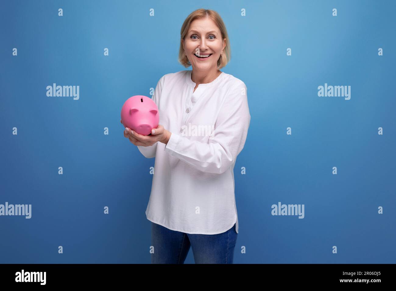 mature woman with blond hair holds savings in a piggy bank Stock Photo ...