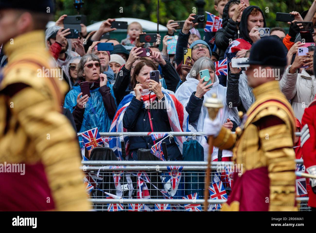 The Mall, London, UK. 6th May 2023. Royal fans in the rain on The Mall during the procession for the coronation of King Charles III capture the action on their mobile phones.   Photo by Amanda Rose/Alamy Live News Stock Photo