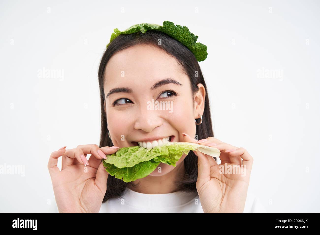 Close up portrait of smiling asian woman eating lettuce, loves cabbage