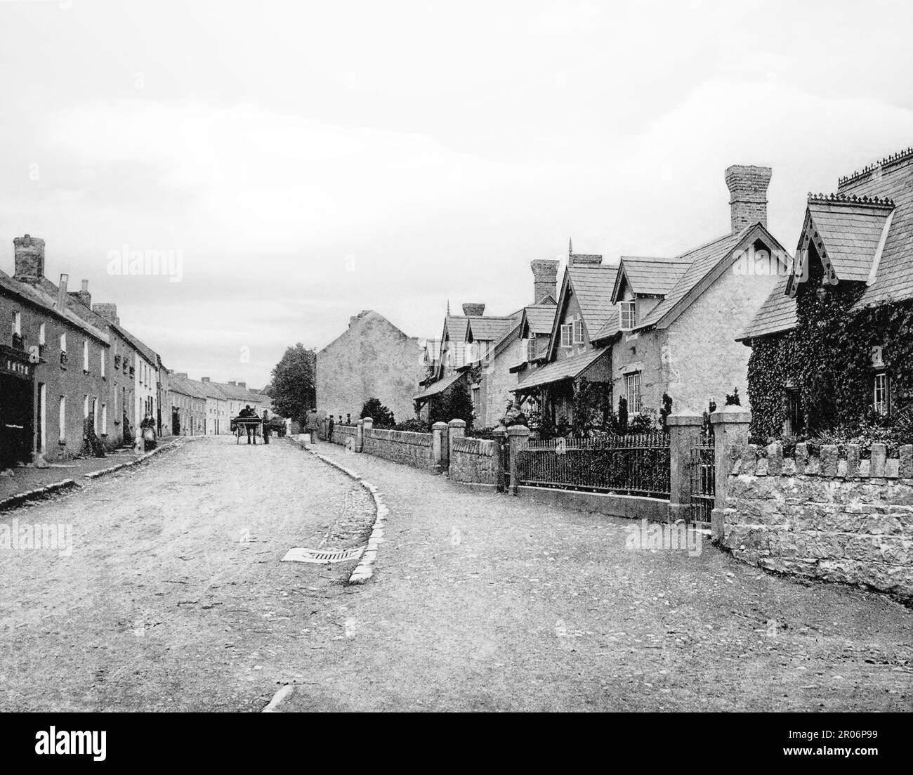A late 19th century street scene with horse and cart beyond the Alms Houses in Gowran, a town located on the eastern side of County Kilkenny, Ireland Stock Photo