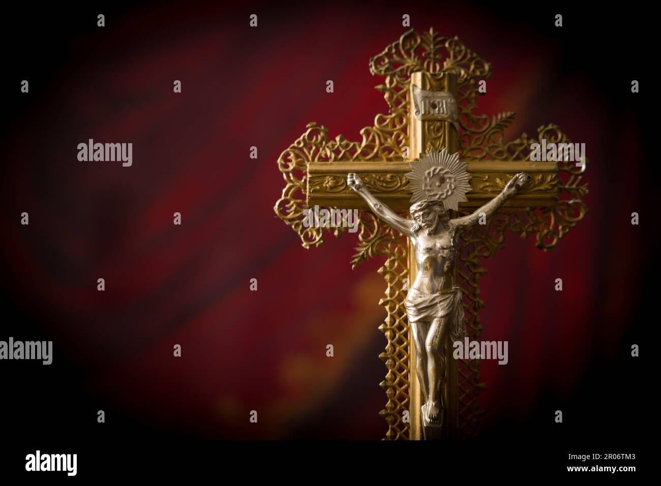 Antique crucifix of wood and gold filigran standing in front of a red velvet curtain Stock Photo