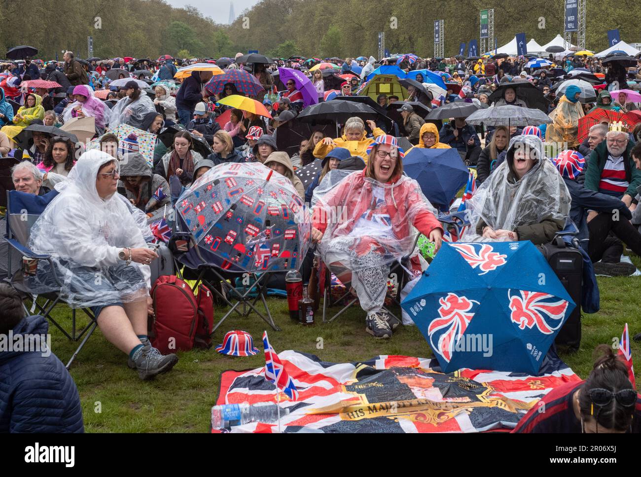 In steady rain, a sea of patriotic British people gathered in Hyde Park, London, UK,  to watch the historic coronation of King Charles III on a large Stock Photo