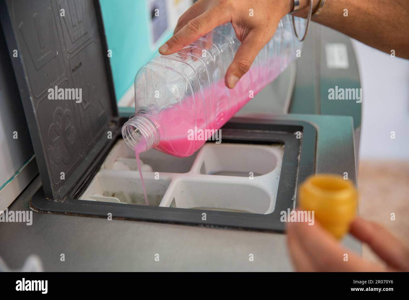 A man pours detergent for washing clothes into the washing machine in a laundromat. Stock Photo