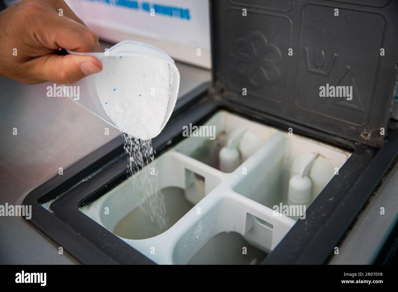 Close-up of a man's hands pouring powder detergent into washing machine in laundry room Stock Photo