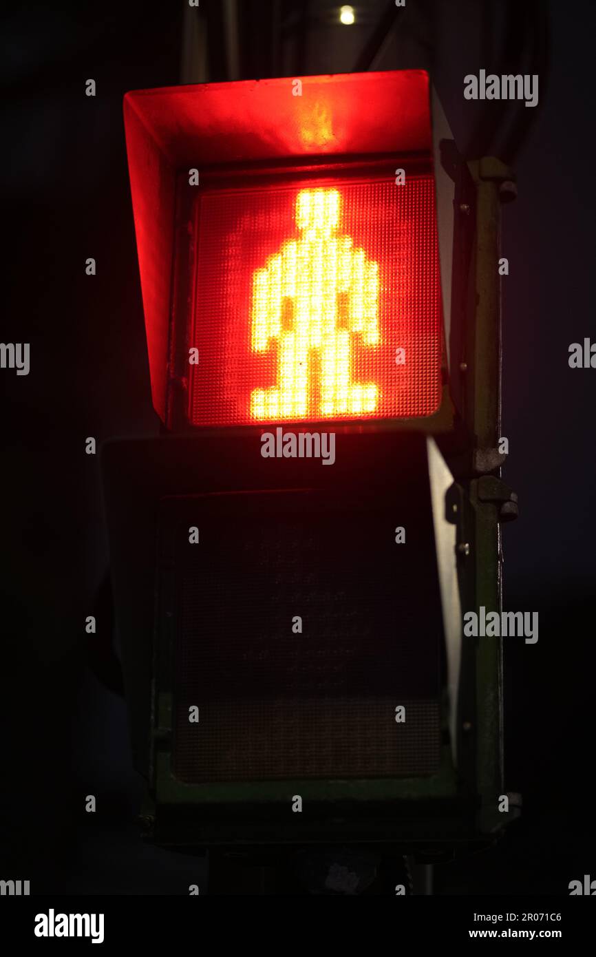 A red traffic signal indicating to stop cross the street at night Stock Photo