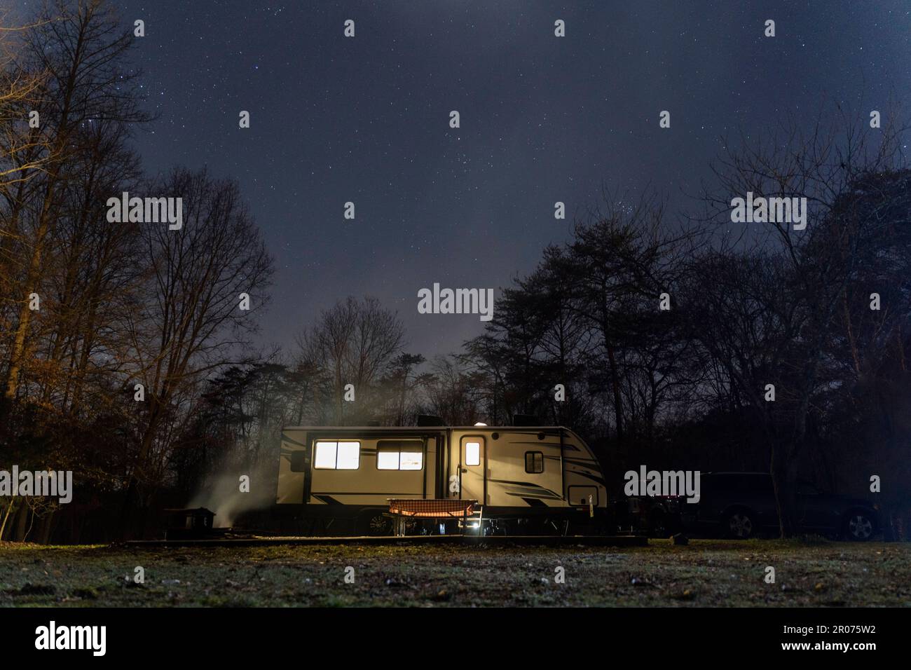 A camping house on lush green meadow illuminated by the star-filled ...