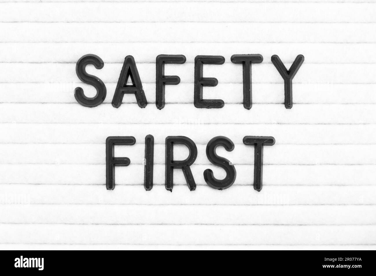 Black color letter in word safety first on white felt board background