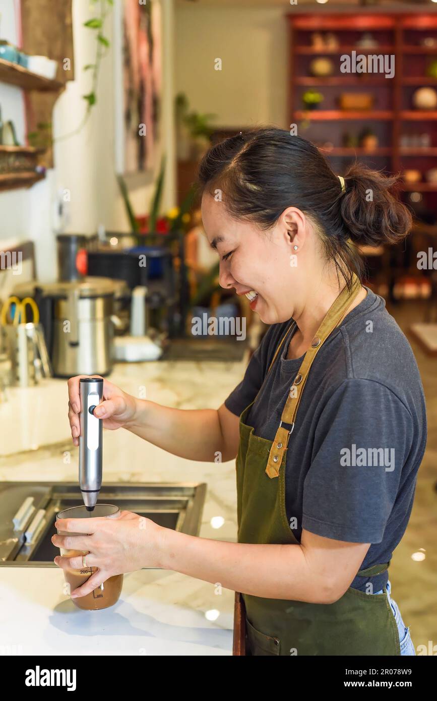 Vietnamese barista using a mixer for condensed milk in glass cup for
