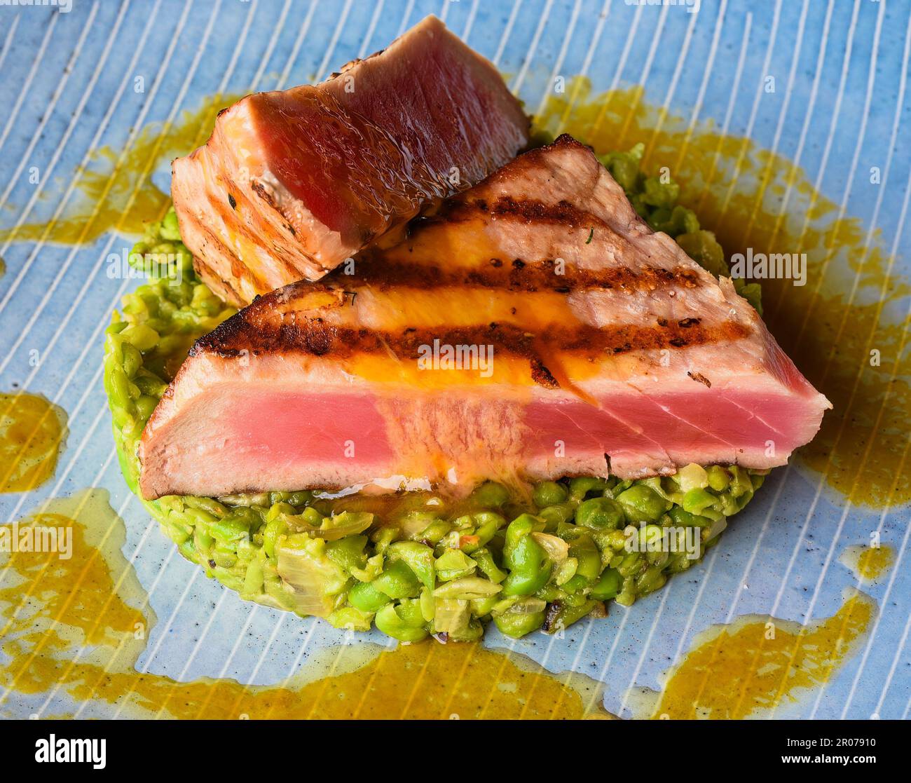 Tuna steak medium rare served with peas isolated on black background