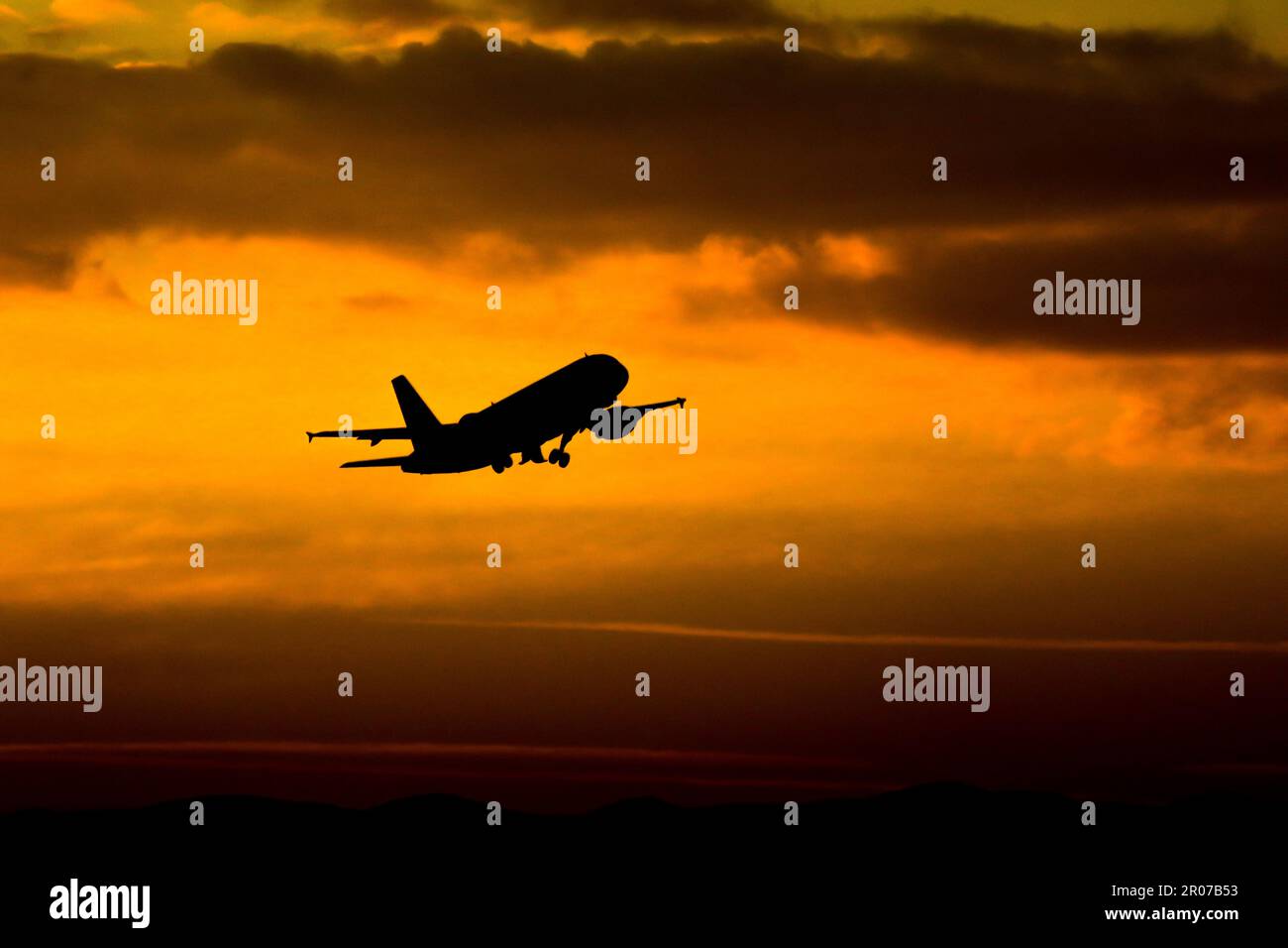 A silhouette of an airplane flying through the sky at sunset Stock ...