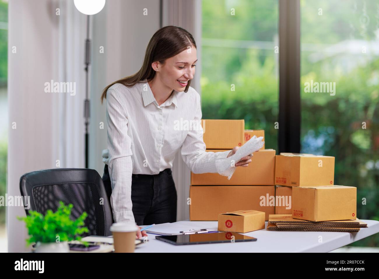 Concept of parcel delivery and selling online,Retailer Using a calculator  to calculate sales for the day on an online store for pack into the parcel  b Stock Photo - Alamy