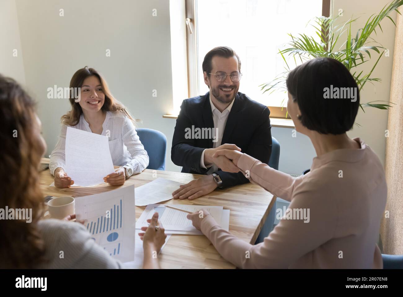 Two business people shaking hands after making deal in office Stock Photo