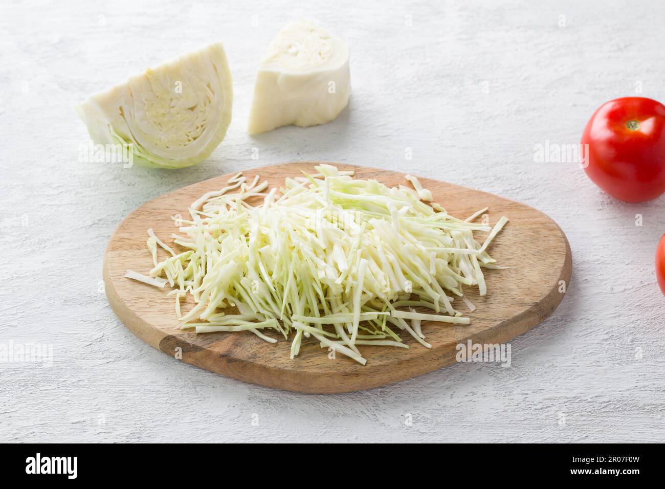 Wooden board with shredded cabbage on a light gray background. Cooking ...