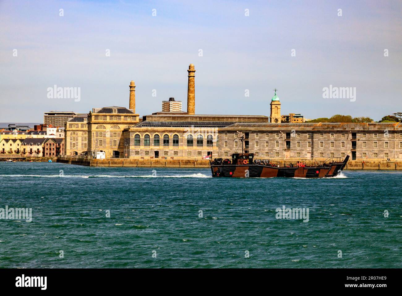 A camouflagued landng craft passes Royal William Yard, a former Royal Navy victualling yard in Plymouth, Devon, England, UK Stock Photo