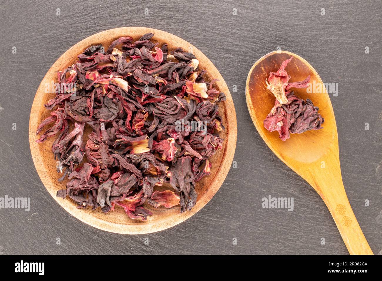 Dry fragrant karkade tea with wooden saucer and wooden spoon on slate ...