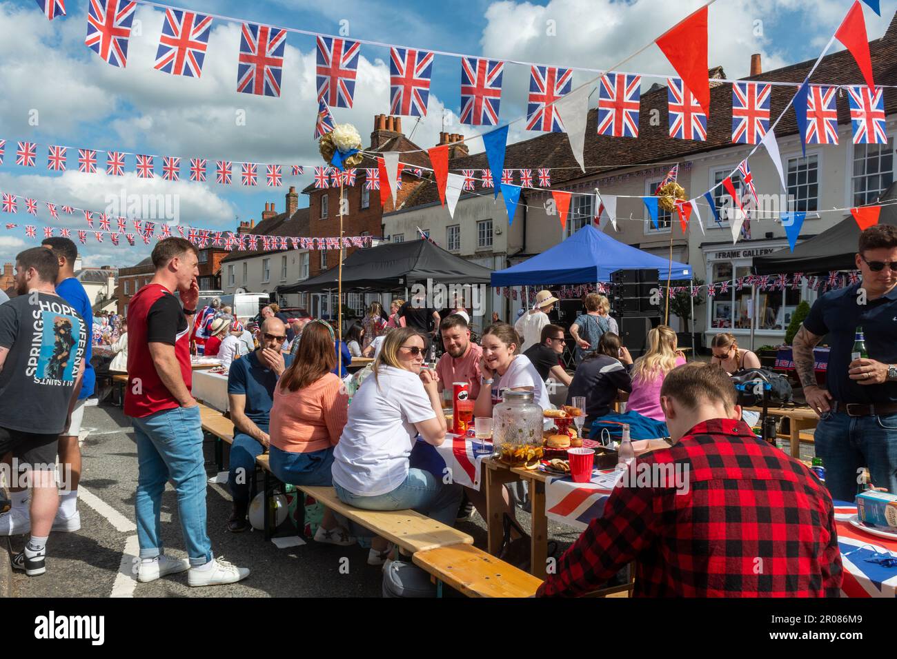 May 7th, 2023. Odiham, Hampshire, England, UK. The long weekend of festivities for the Coronation of King Charles III and Queen Camilla continued with a large street party along the village High Street, which was decorated with red white and blue bunting. It was a sunny afternoon for the popular event, which attracted lots of people to celebrate the royal occasion. Stock Photo