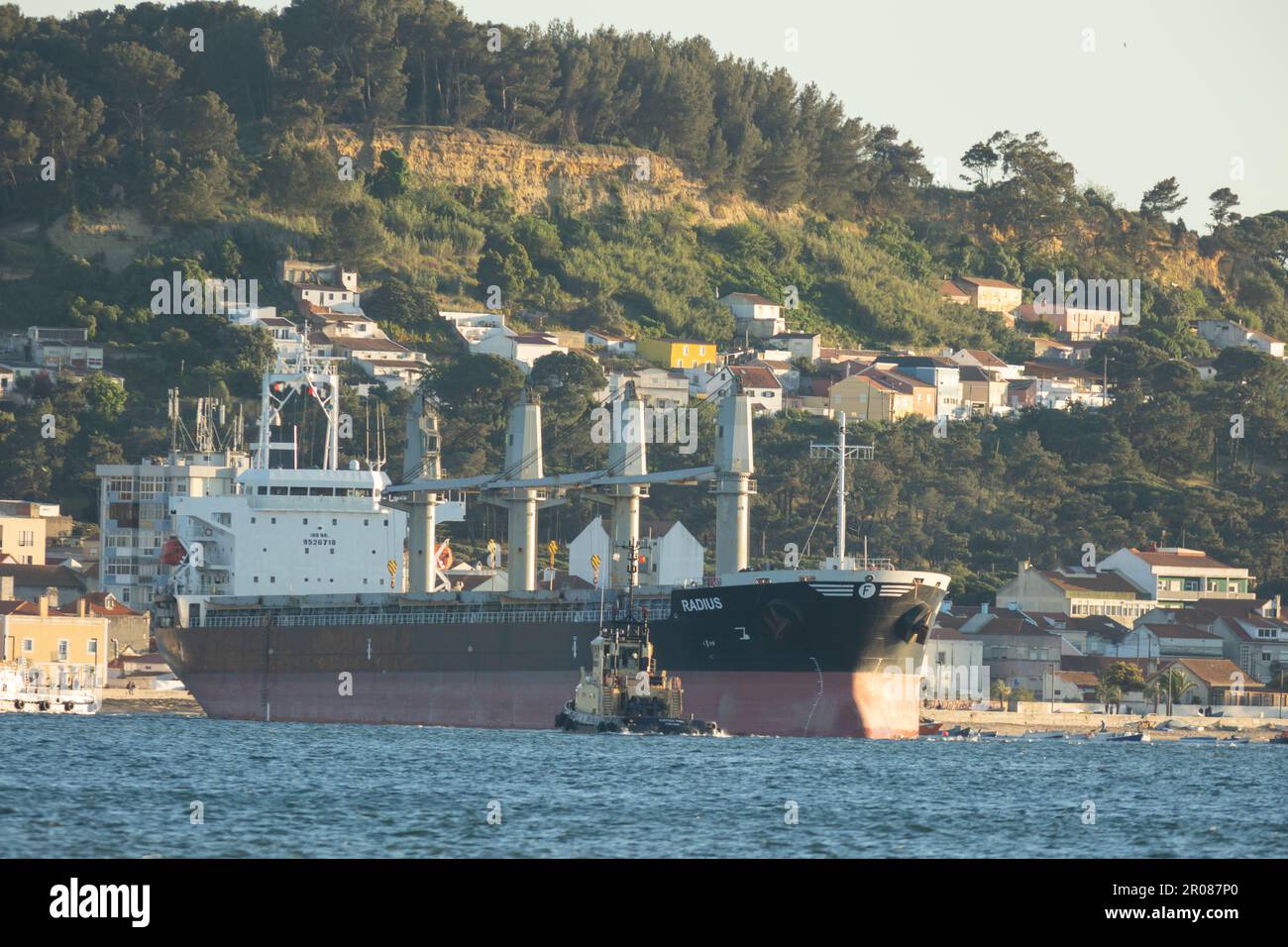 11 April 2023 Lisbon, Portugal: a large cargo ship and a small boat nearby Stock Photo