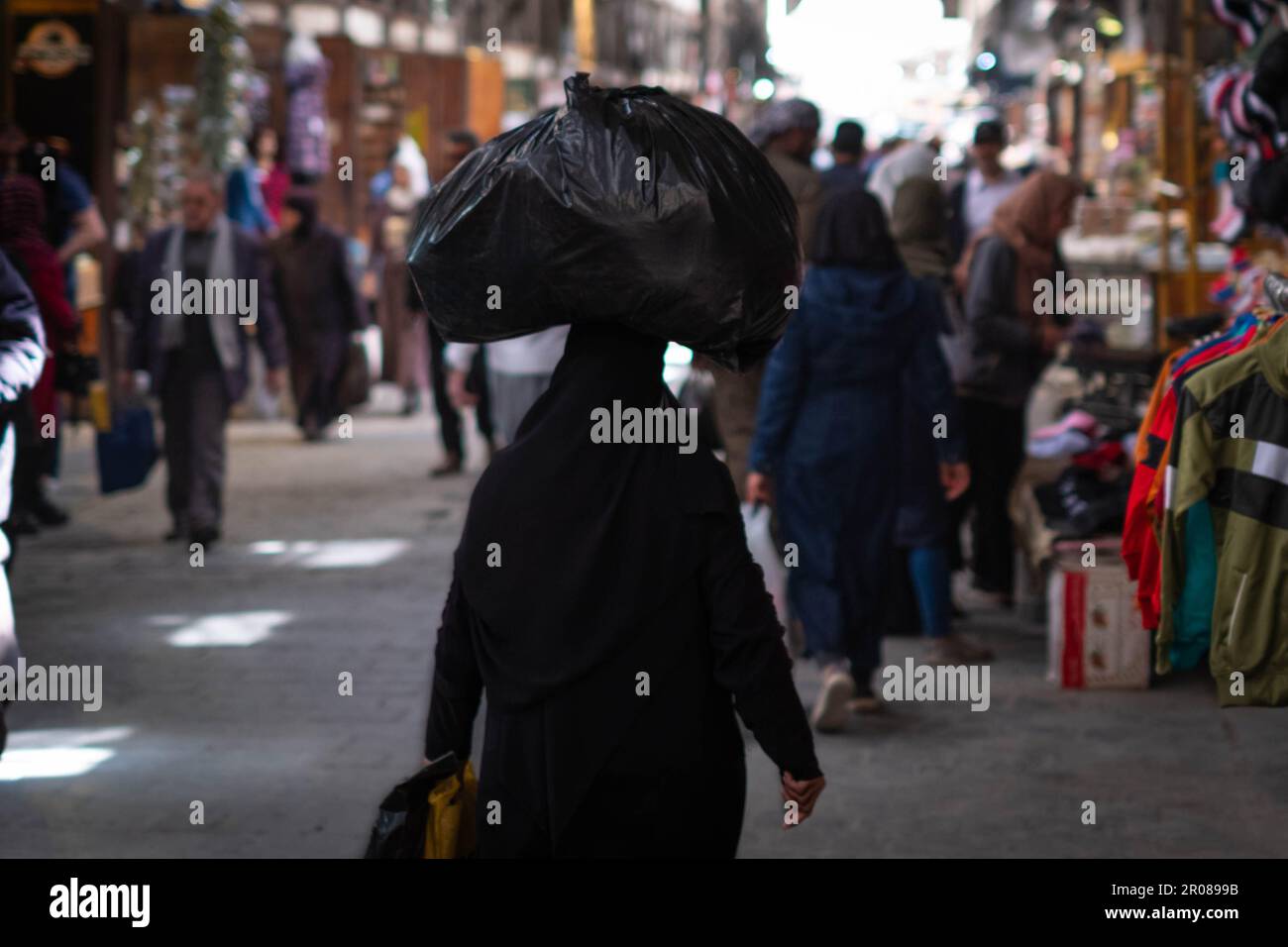 Arabic woman carries bag on head on street market Stock Photo