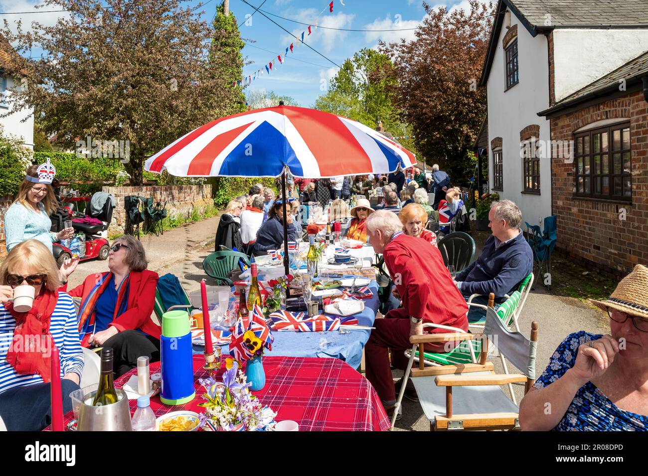 Brightwell-cum-Sotwell, Oxfordshire, UK. 7th May, 2023.  Villagers packed a closed section Brightwell Street for their Street Party celebration of the coronation of HRH King Charles. Tables and revellers occupied an estimated 200M of road. Live music would later entertain late into the evening. Credit: Stephen Bell/Alamy Live News Stock Photo