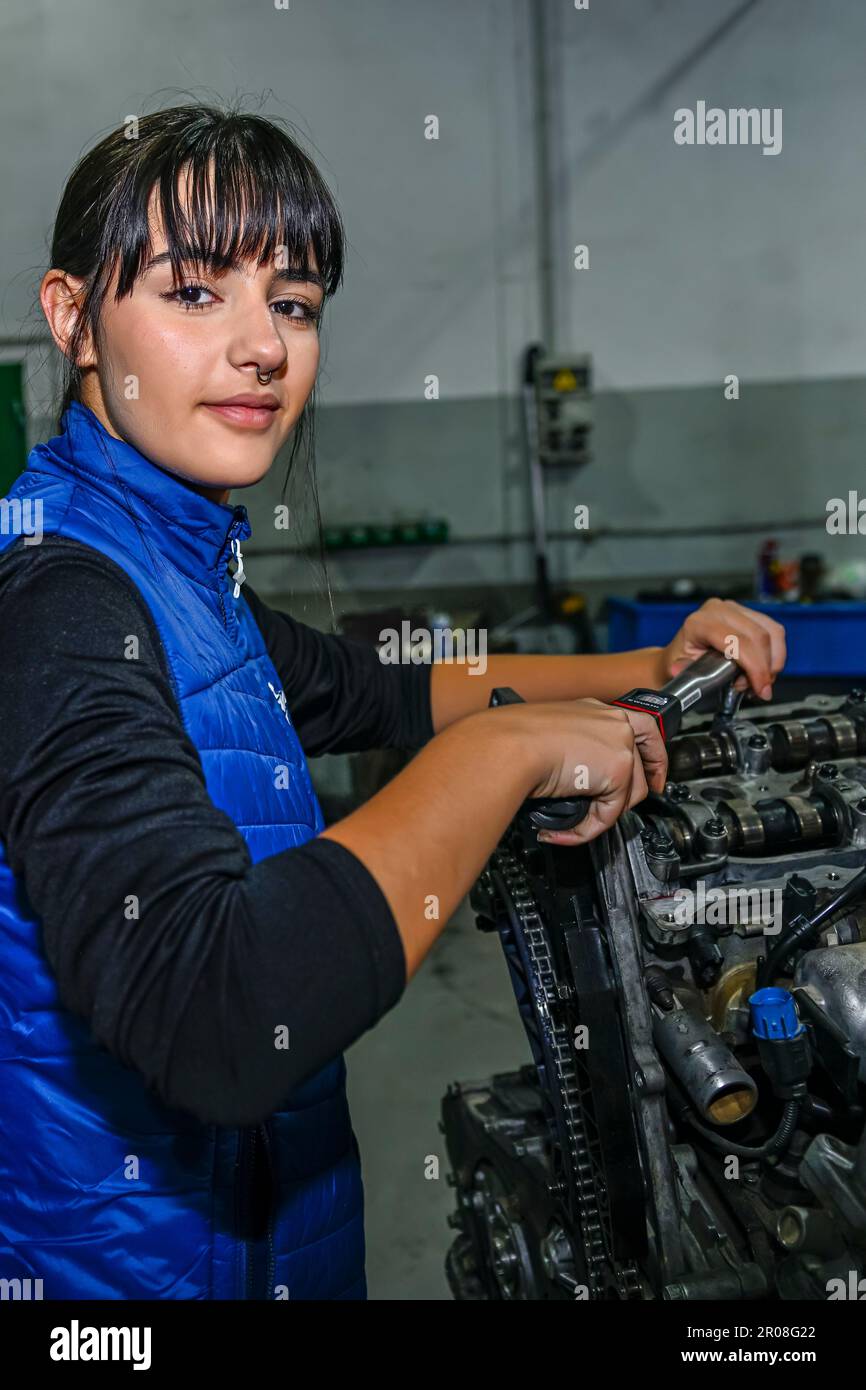 Young female mechanic, working on the repair of a car engine Stock