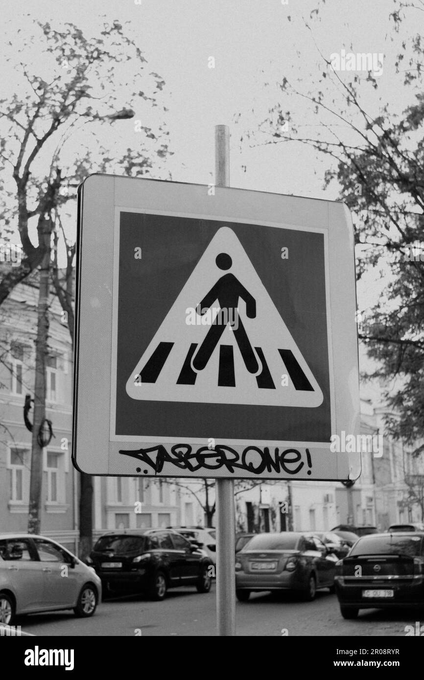 a monochrome shot of a vandalized pedestrian crossing sign Stock Photo