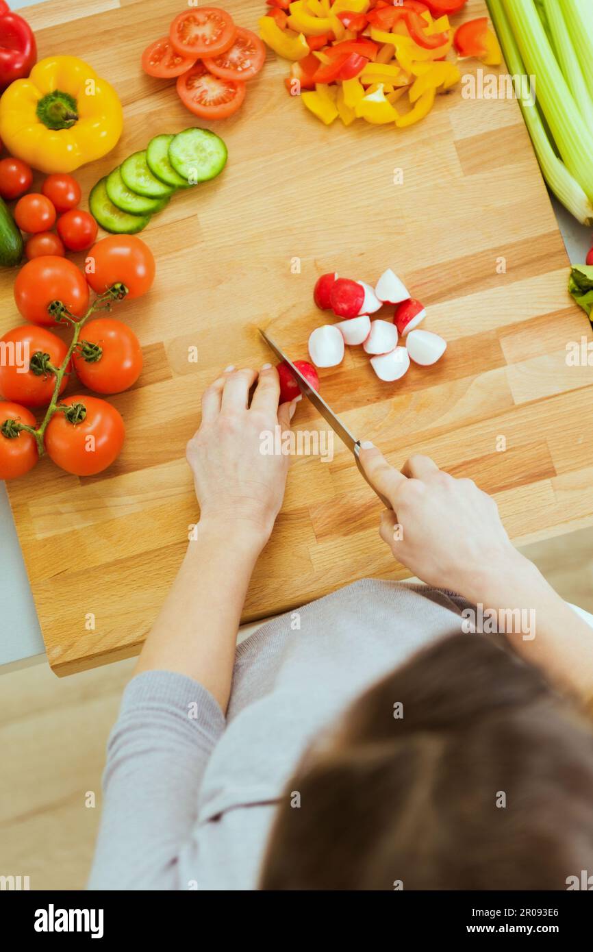 Woman slicing vegetables on cutting board Stock Photo