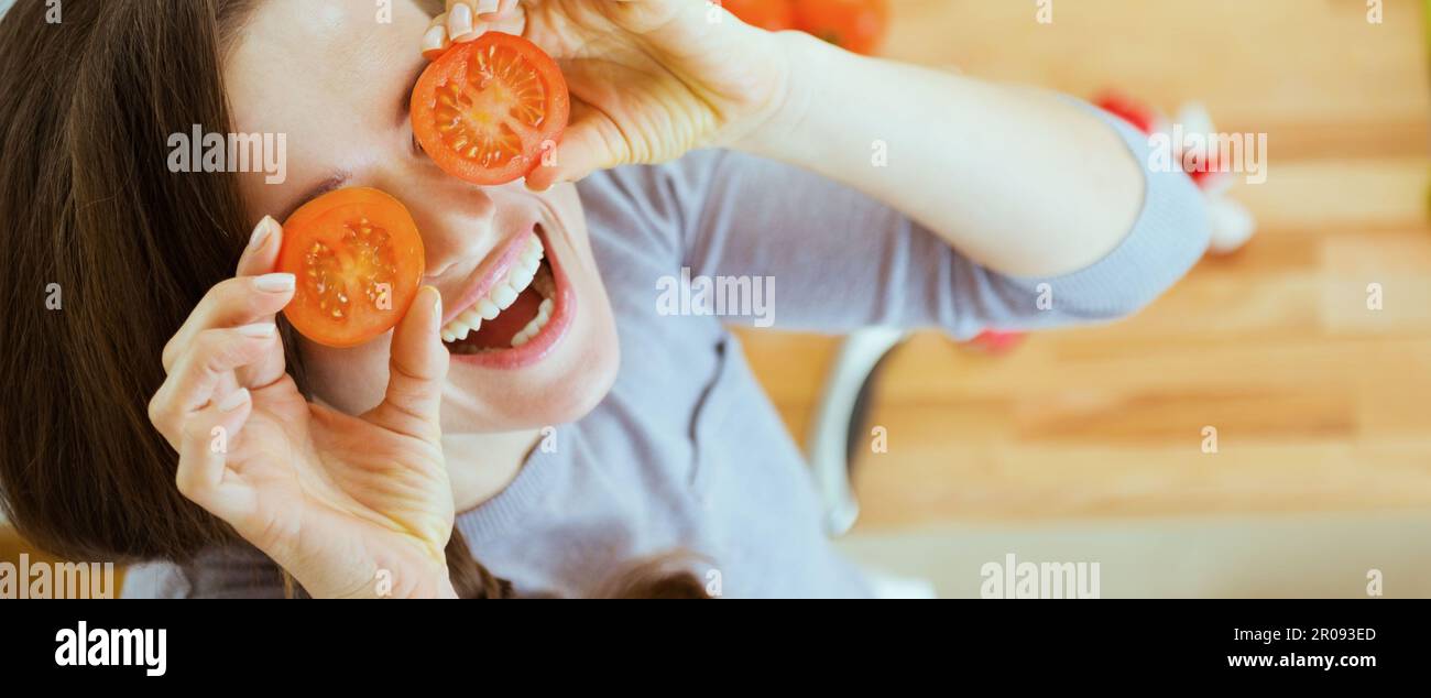 Smiling young woman holding cherry tomatos in front of face Stock Photo ...