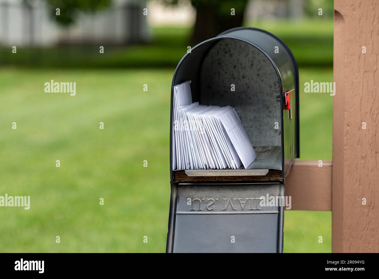 Mailbox full of letters and junk mail. Mail delivery, post office and postal service concept. Stock Photo