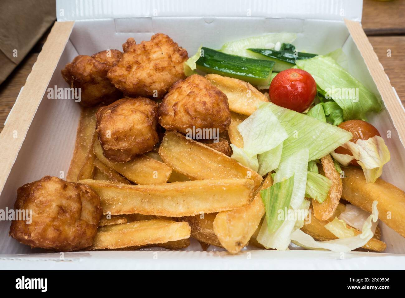 Chicken nuggets and chips with salad in a decomposable box Stock Photo