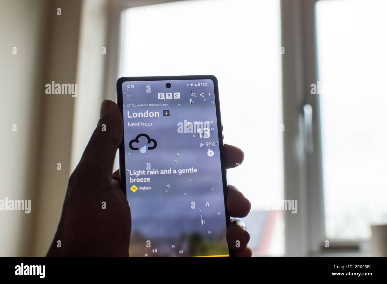 London weather app with grey skies through window Stock Photo
