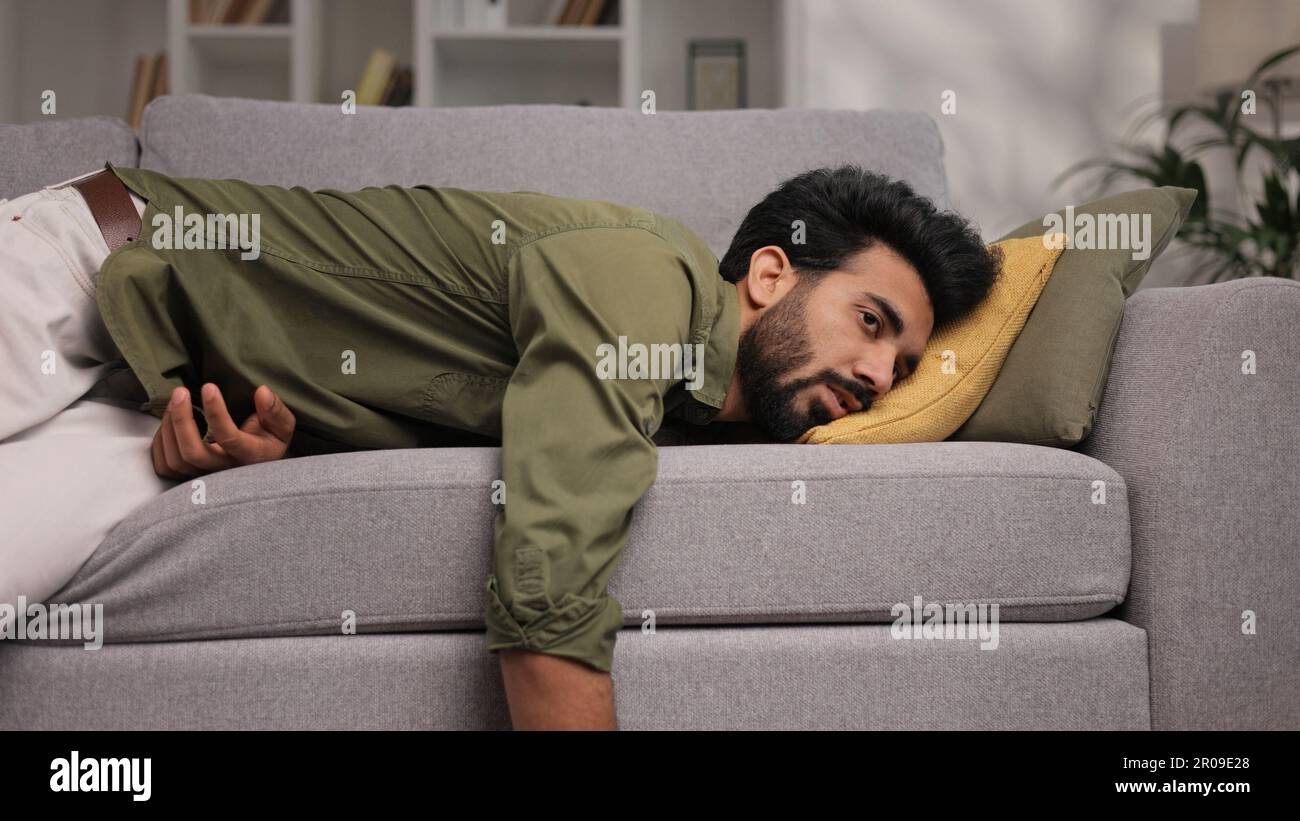 Tired Indian boy slumps on couch feeling listless. Feeling depressed ...
