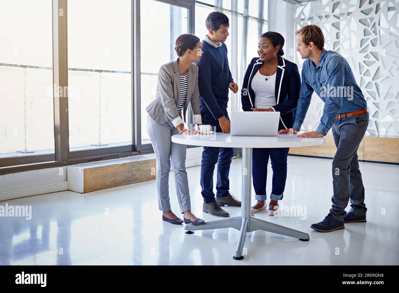 Our new site is attracting more clients. a group of coworkers working together on a laptop in an office. Stock Photo