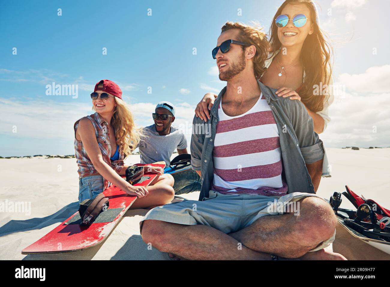 The best day are spent out on the dunes. a group of young friends sandboarding in the desert. Stock Photo