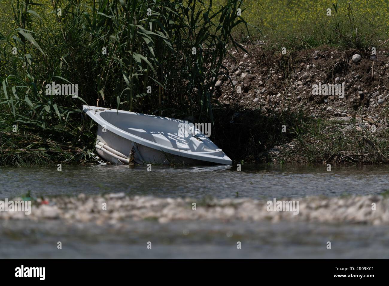 A bath tub dumped by the river. Destruction of the environment. Stock Photo